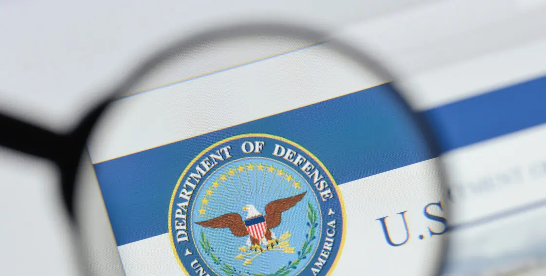 A magnifying glass held up to the Department of Defense logo